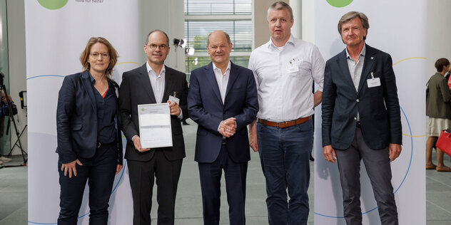 Pfarrer Erwin Sergel (2.v.l.) und Martin Reents (2.v.r.) vom Bunten Haus in Miesbach mit Bundeskanzler Olaf Scholz (M.), Schirmherr von startsocial e.V., und den Coaches Julia Bourgett und Winfried Holz. 