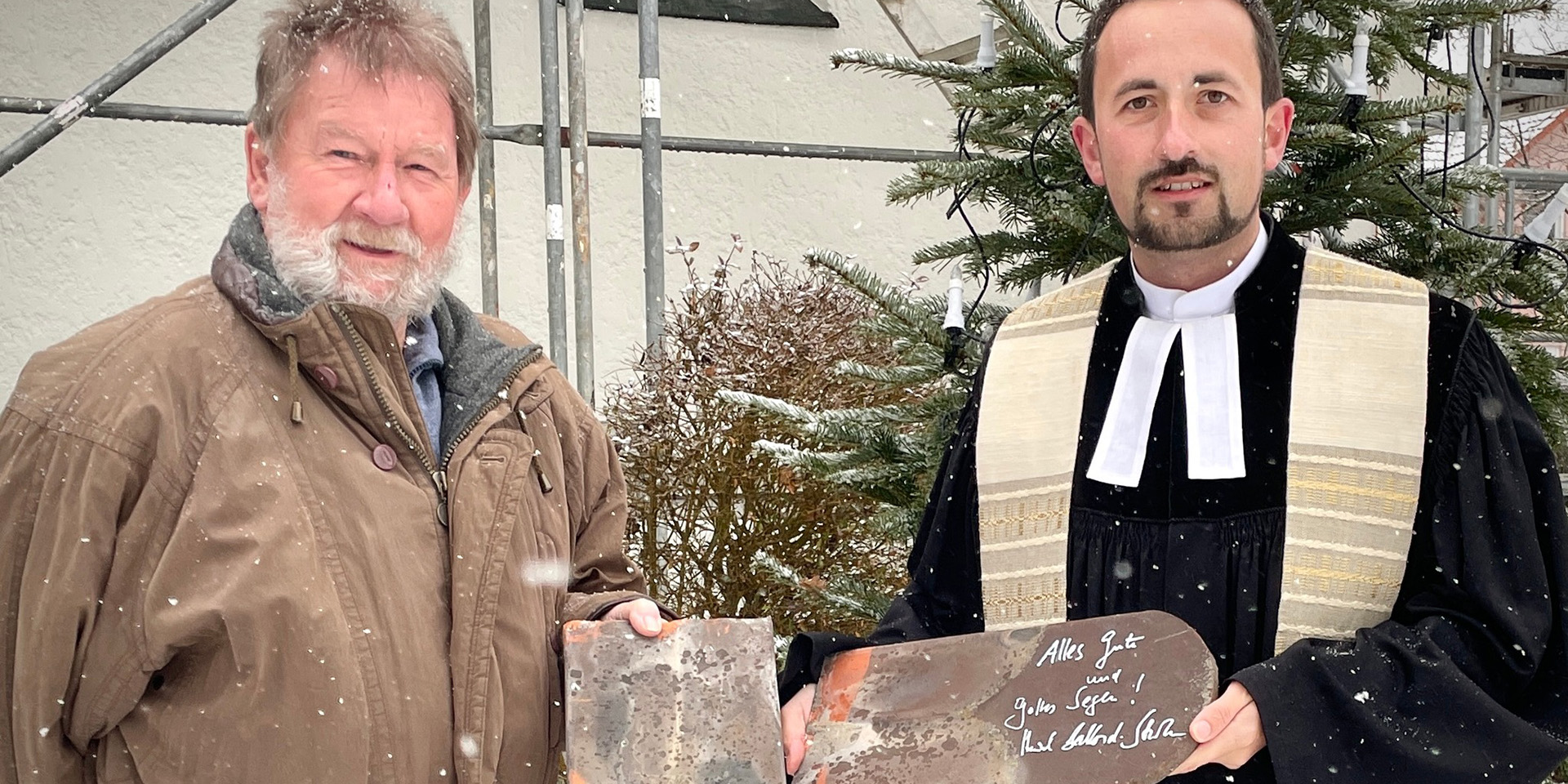Vertrauensmann Ulrich Gerlach und Pfarrer Stefan Fischer zeigen zwei signierte Ziegel.