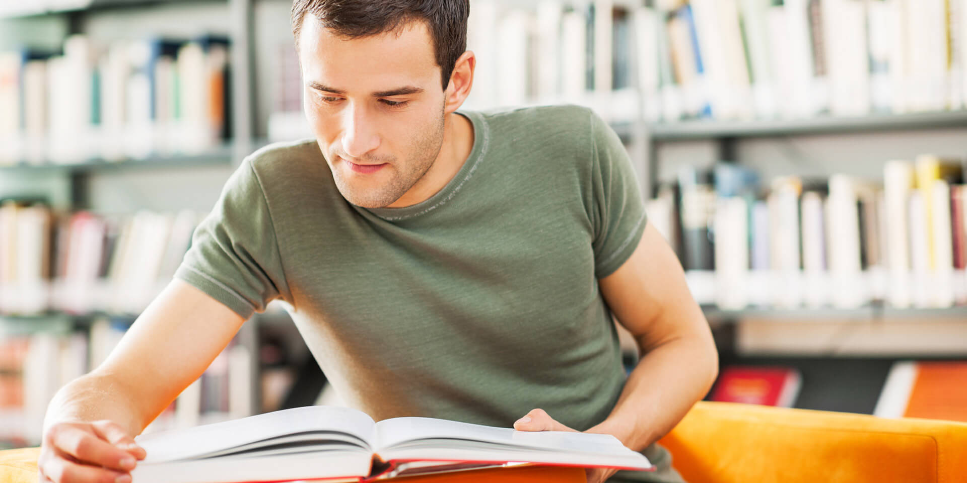 junger Mann liest vor Bücherwand junger Mann liest