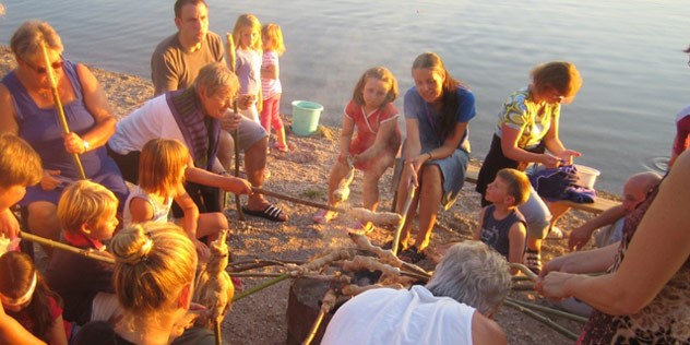 Das Bild zeigt Menschen, die an einem Strand grillen Menschen grillen am Strand,© Amt für Gemeindedienst / Kirche unterwegs