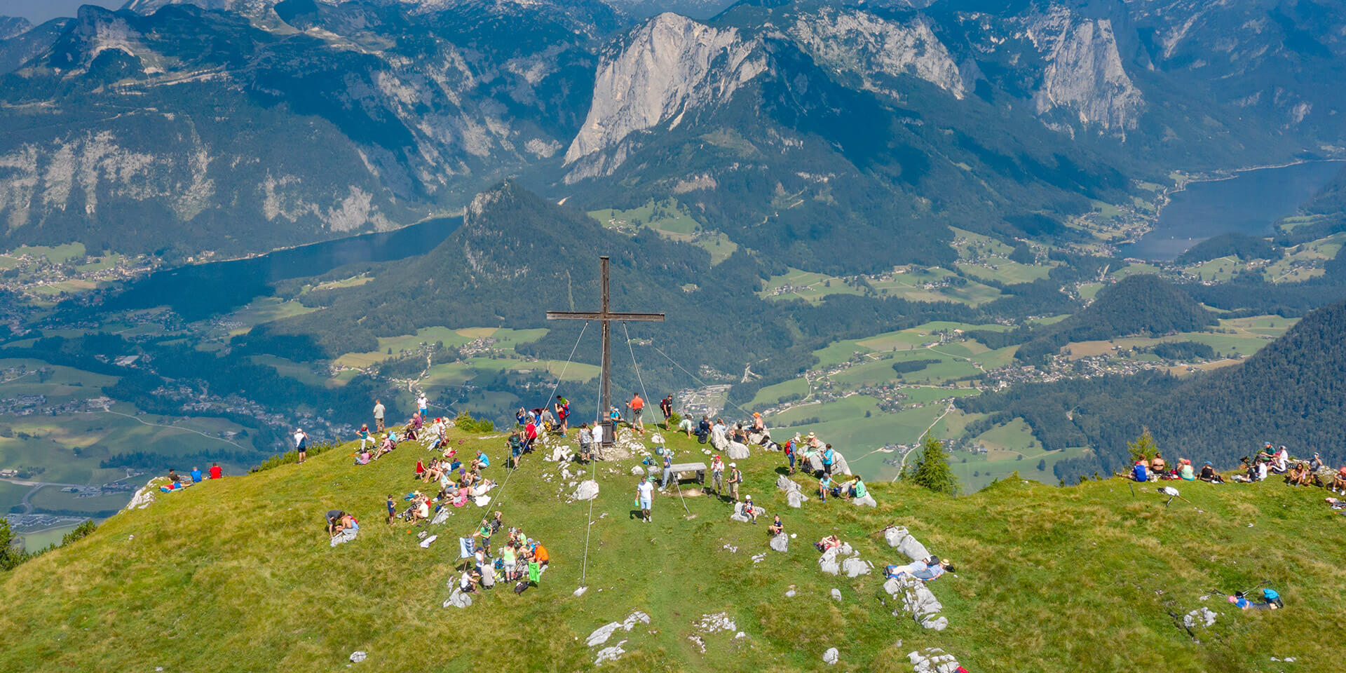 Das Bild zeigt ein helles Kreuz vor einer dunkelbrauen Wand. Das Bild zeigt ein Kreuz