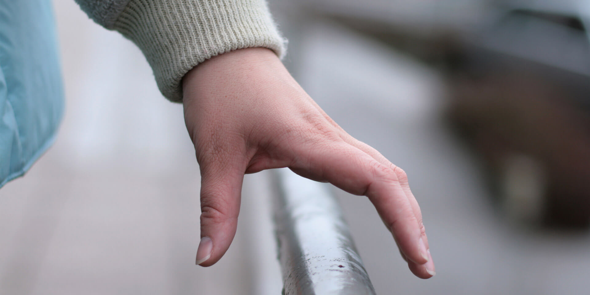 Das Bild zeigt eine Hand an einem Geländer Hand am Geländer