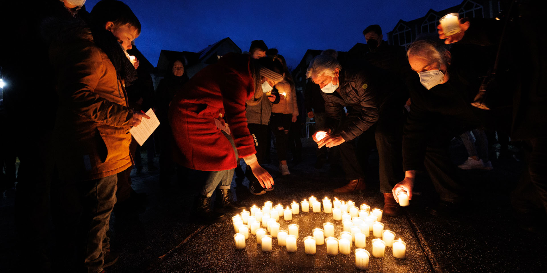 Menschen entzünden Kerzen bei einem Friedensgebet 