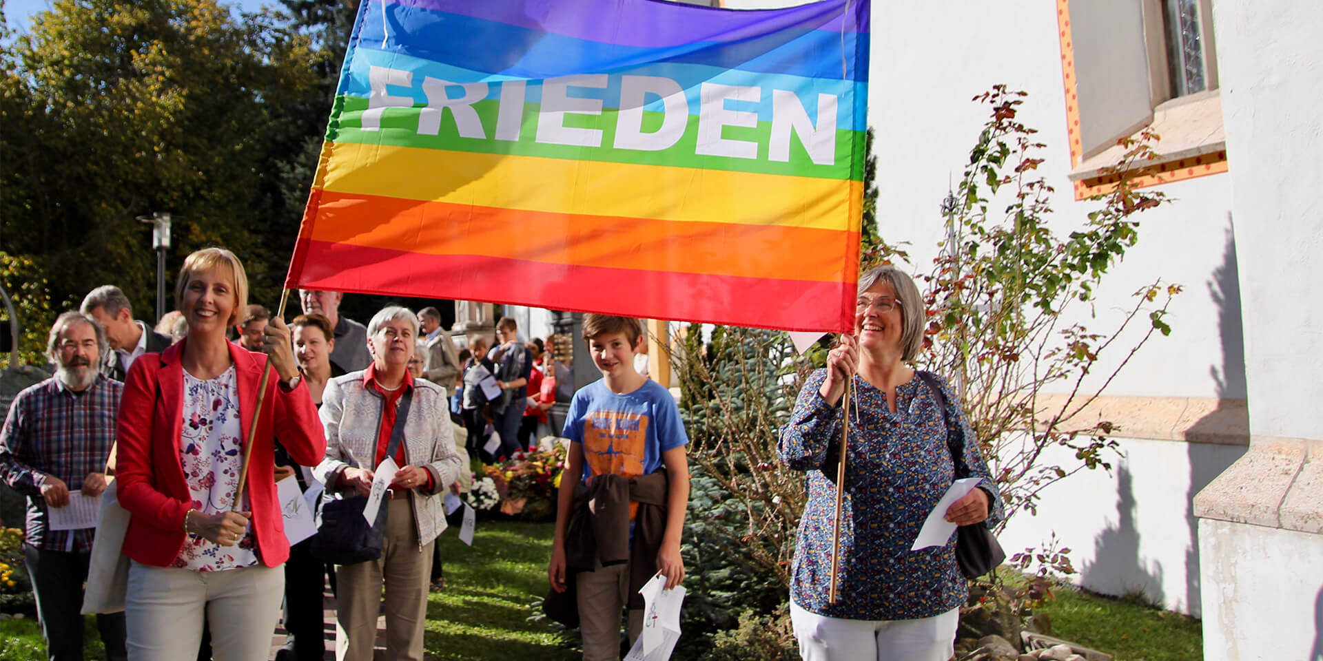 Organisatorinnen des Pasinger Friedenswegs führen 2023  mit einem Friedensbanner den Zug von Stationn zu Station an. 