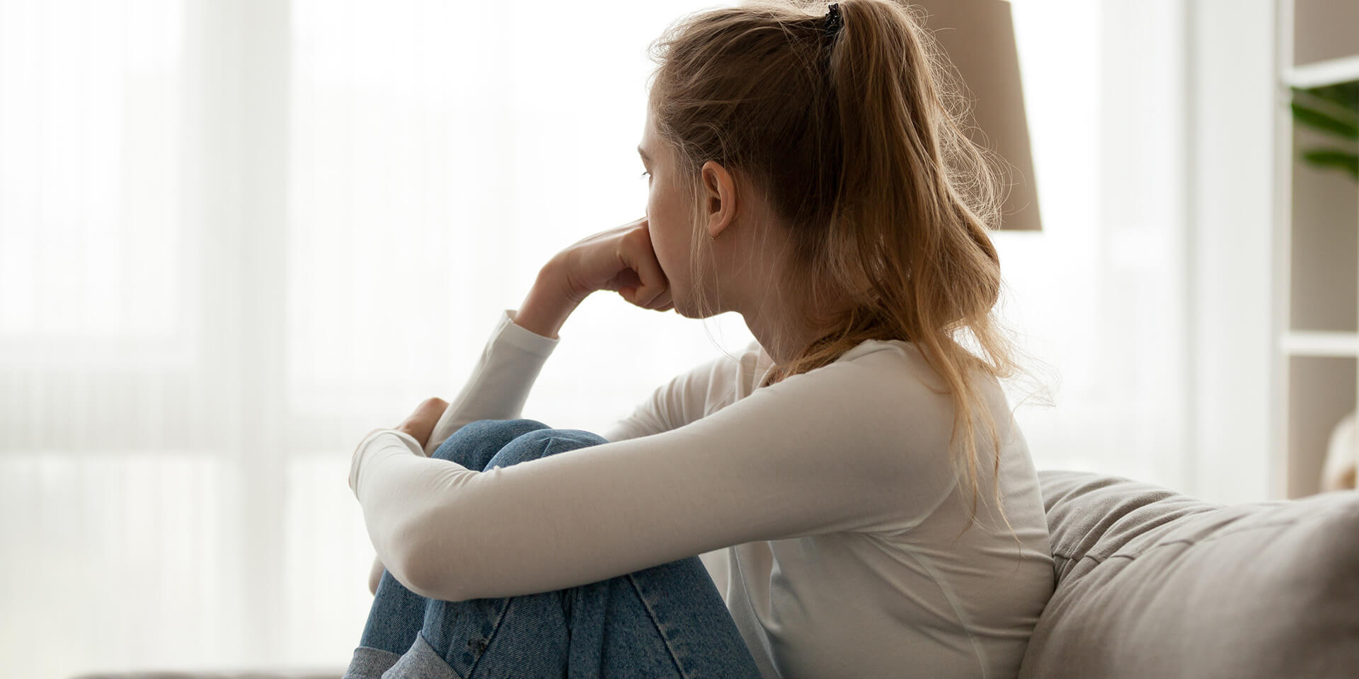 Junge Frau blickt Nachdenklich aus dem Fenster 