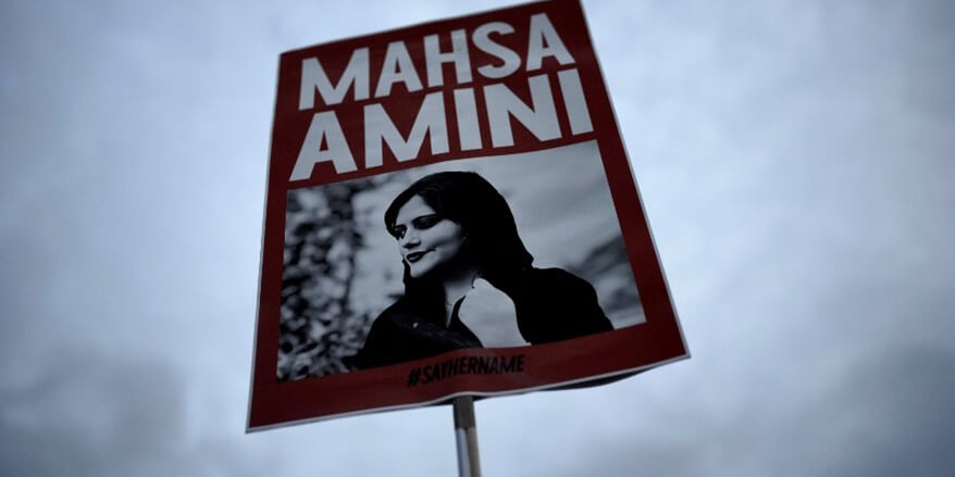 Plakat mit Mahsa Amini, das bei einer Demonstration in die Höhe gehalten wird