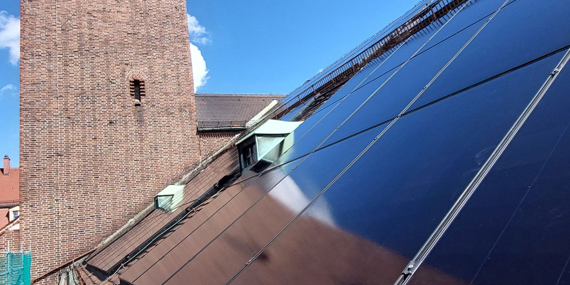Der Kirchturm spiegelt sich in den Solarpanels., &copy; ELKB
