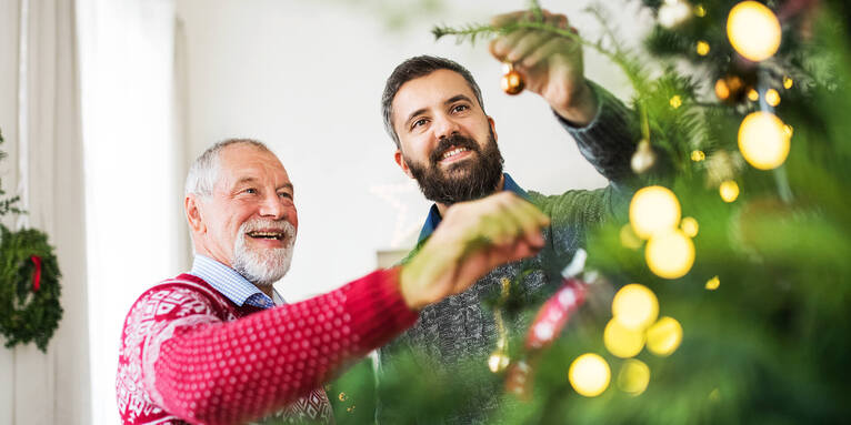 Zwei Männer beim Christbaumschmücken , © gettyimages/halfpoint