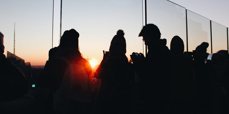 Menschen schauen in den Sonnenuntergang , © Unsplash / Alina Grubnyak 