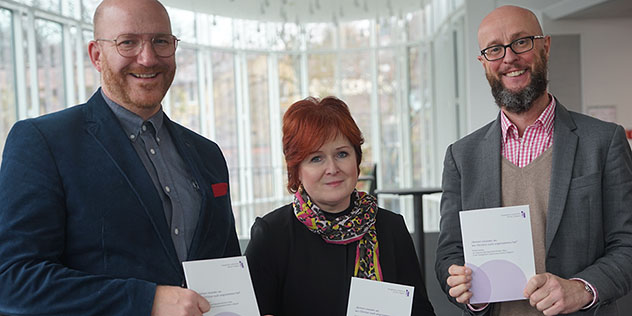 Die Synodalen Norbert Roth und Christina Flauder sowie der theologische Referent der Landessynode, Ralf Frisch, mit der Handreichung, © ELKB