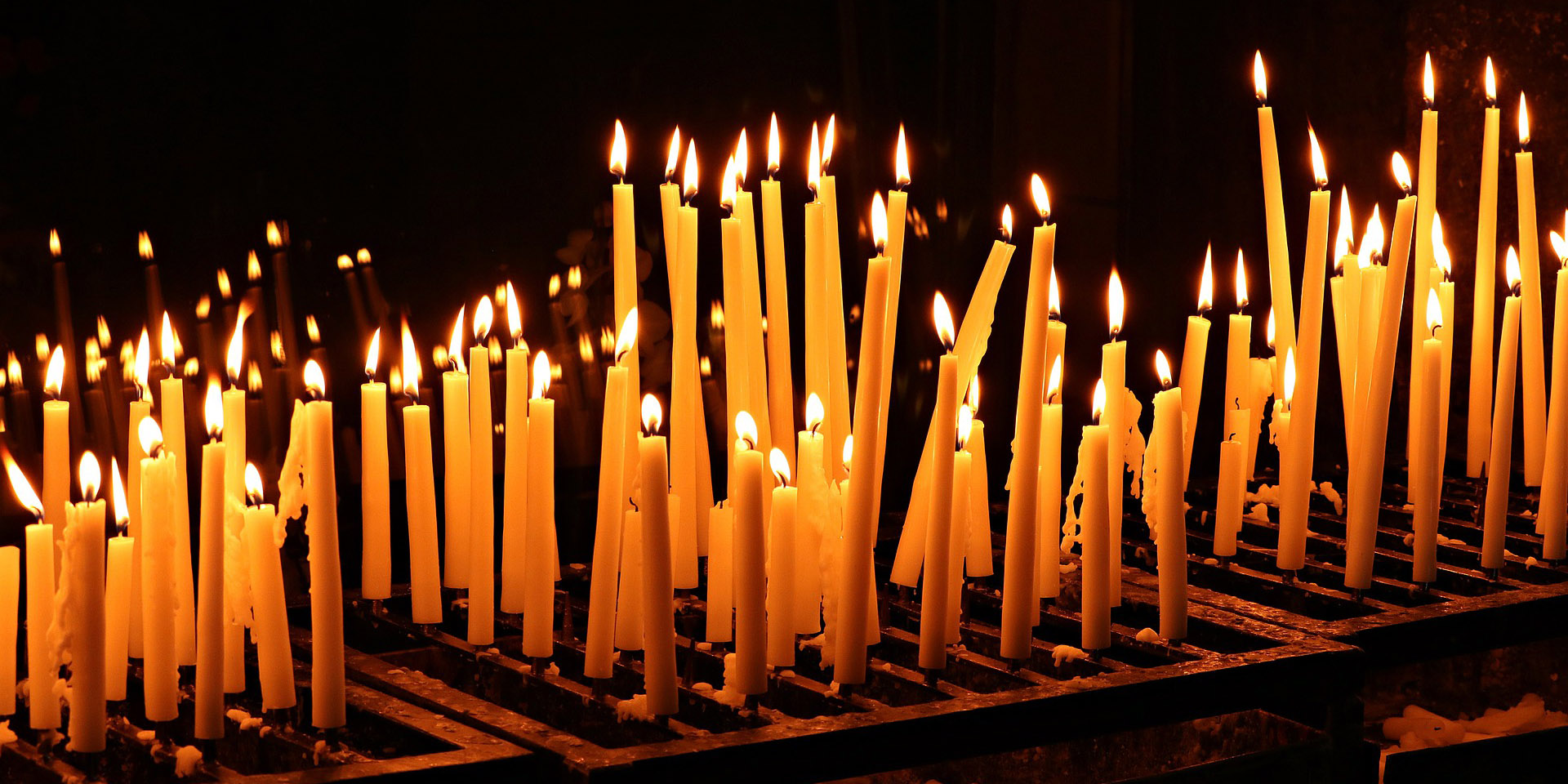 Zahlreiche angezündete Kerzen im Dunkeln 