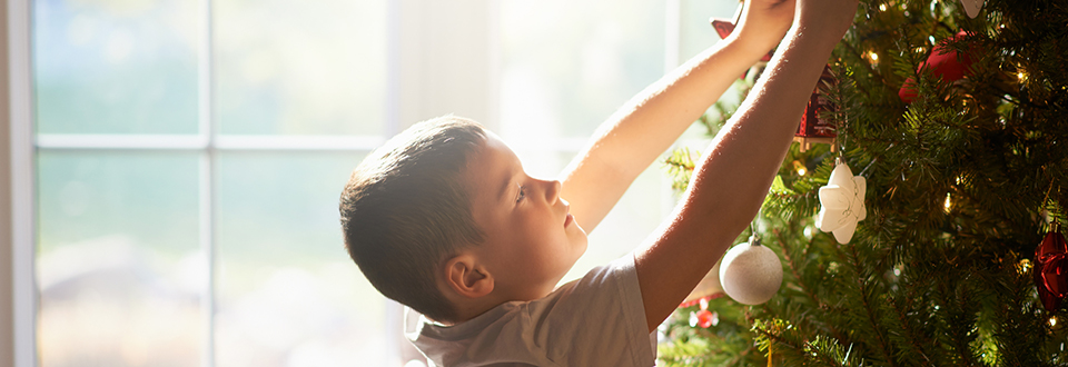 Junge schm&uuml;ckt den Weihnachtsbaum