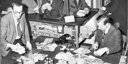 Fotographie einer Umtauschstelle mit Reichsmark-Bündeln auf den Schreibtischen